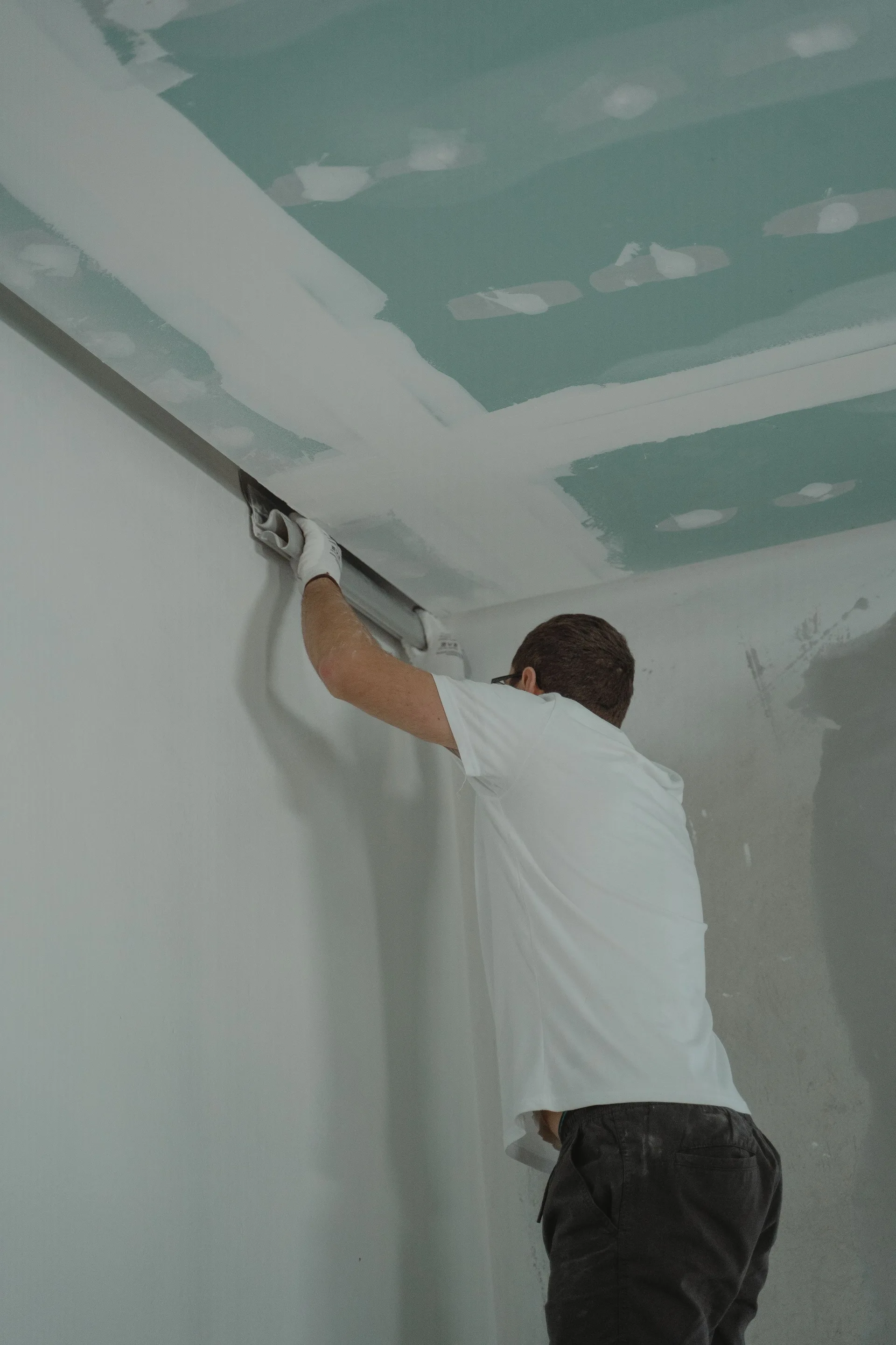 Handwerker verspachtelt den Übergang zwischen Wand und Gipskartondecke